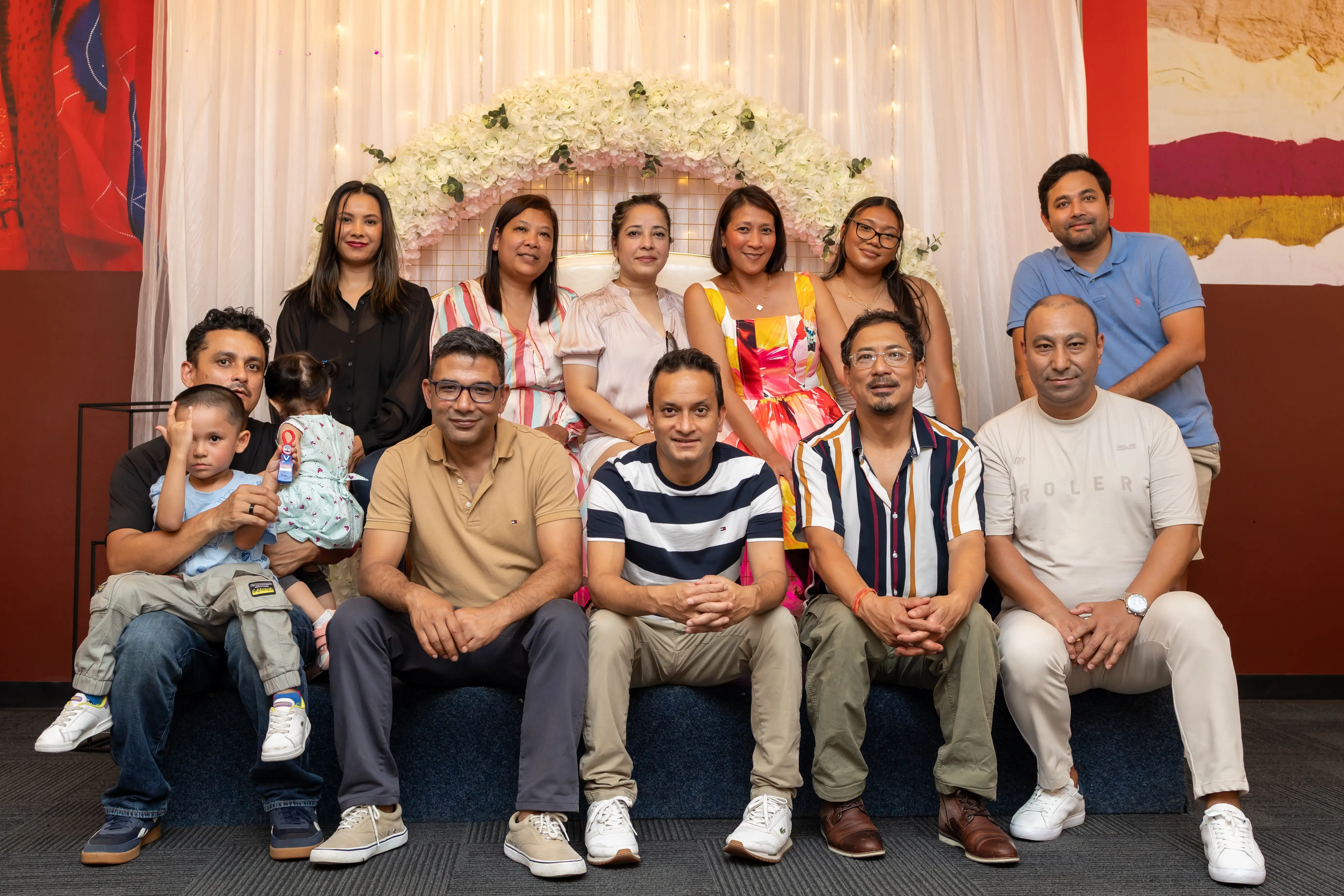 A large group of people gathered at a function, including adults of different ages, a man holding a baby. They are posing for a group photo, all smiling and enjoying themselves. All are wearing semi-formal and enjoying the function at Third Eye Windsor, 515 George St, South Windsor NSW 2756.
