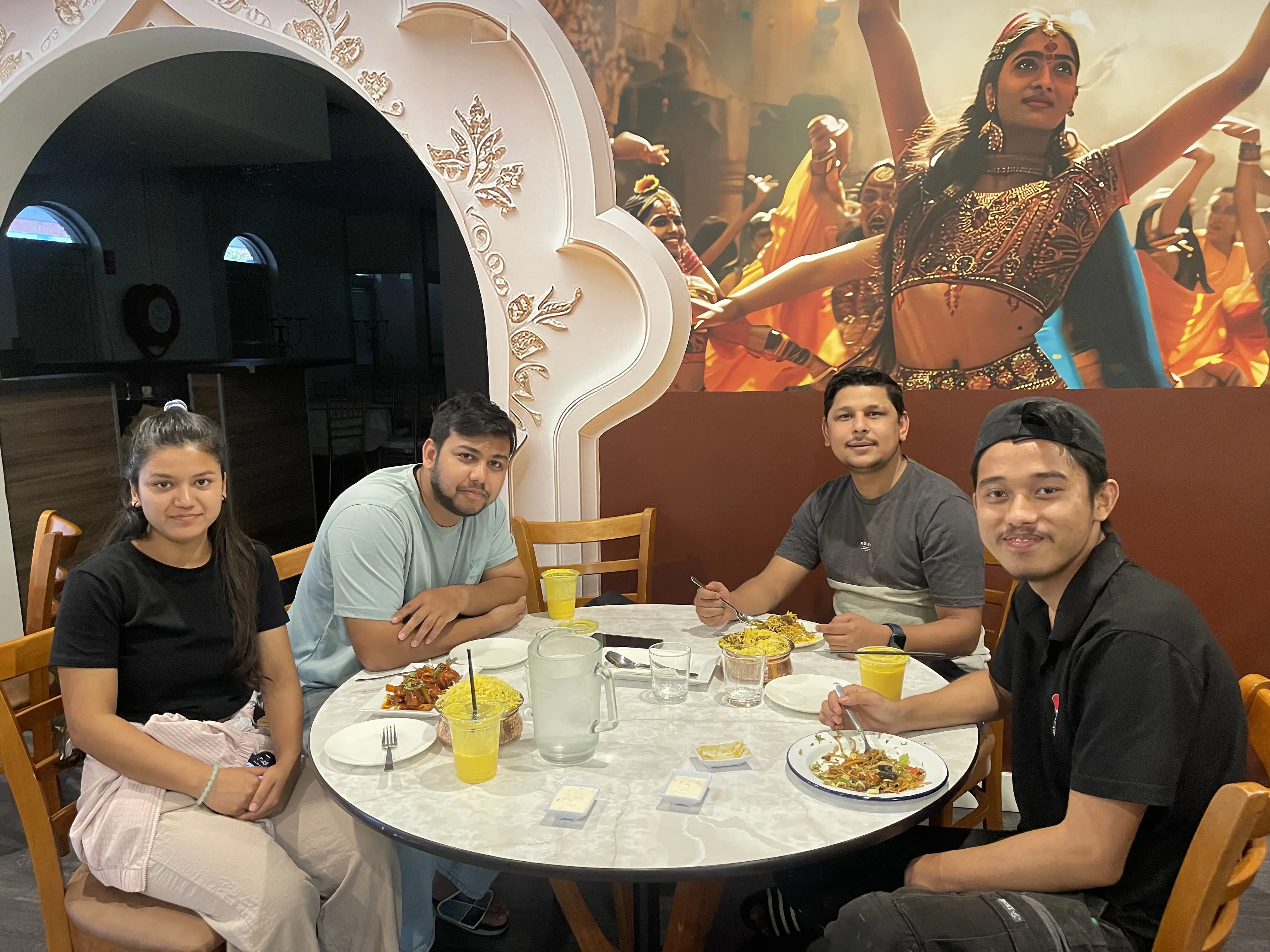 Three men and one woman in semi-formal attire enjoying Nepalese and Indian cuisine along with fresh drinks, seated at a dining table in a restaurant at Third Eye Windsor, 515 George St, South Windsor NSW 2756.